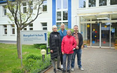 Auf dem Bild sieht man vier Personen der Deutschen Rentenversicherung, vor dem Gebäude der Burgdorf-Schule