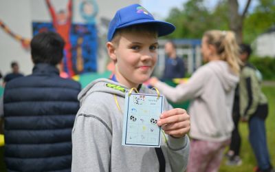 Auf dem Bild sieht man einen Jungen wie er seine Stempelkarte zeigt.
